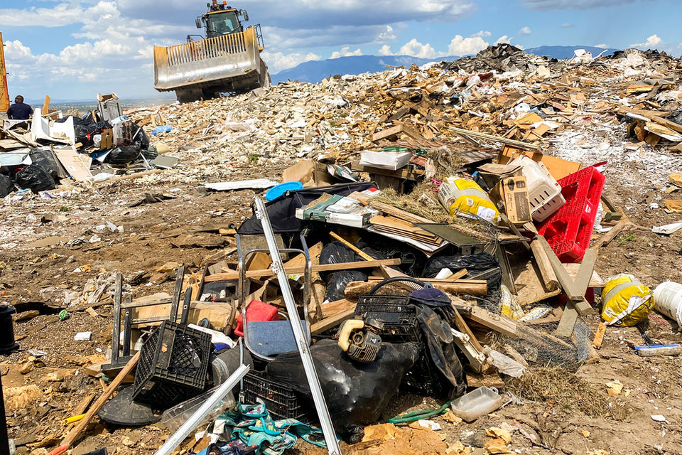 Green dumpster on truck with Sandia Mountains backdrop